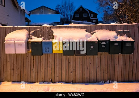 Tromso, Norvège - Décembre 2018 : rangée de boîtes aux lettres colorées sur une clôture en bois en face d'un immeuble résidentiel en hiver Banque D'Images