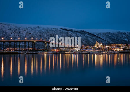 Tromso, Norvège - Décembre 2018 : Port et port avec Tromso célèbre pont à travers le détroit d'Tromsoysundet dans l'arrière-plan, photographié de nuit Banque D'Images