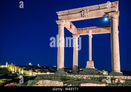 La lune s'élève au-dessus de la ville illuminée d'Avila et le monument Cuatro Postes, Avila, Espagne Banque D'Images