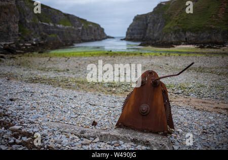 Rusty, un morceau de machiney abandonnés qui a engrenages, repose sur une plage rocheuse à Geodha à Smoo Cave Smoo, une grande cave et d'eau douce mer combiné cave Banque D'Images