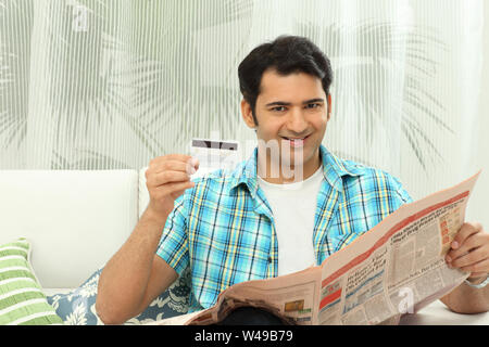 Man reading newspaper et carte de crédit Banque D'Images