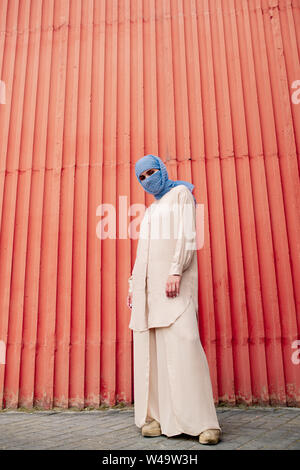 Jeune femme en hijab islamique occasionnels et costume occasionnel par permanent red wall Banque D'Images