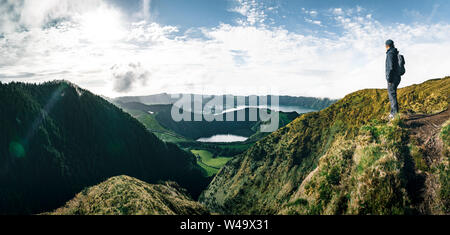 Jeune homme debout touristique donnant sur une vue pittoresque sur le lac de Sete Cidades Sept villes Lake , un lac de cratère volcanique sur l'île de São Miguel Banque D'Images