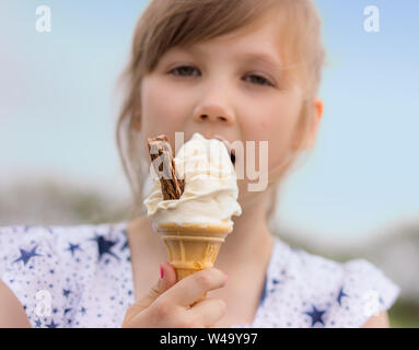 Jeune fille blonde et manger de la crème glacée au chocolat avec flake Banque D'Images