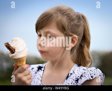 Jeune fille blonde et manger de la crème glacée au chocolat avec flake Banque D'Images