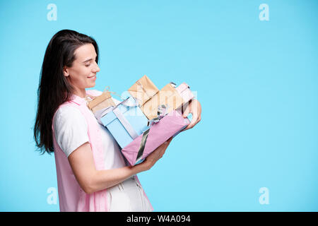 Happy young woman looking at pile de giftboxes dans ses mains Banque D'Images