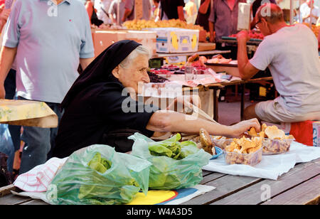 Femme vêtue de noir, la vente de champignons à partir d'une table au décrochage du marché agricole. Dame reprend de spécimen à sac. Zagreb, Croatie Banque D'Images
