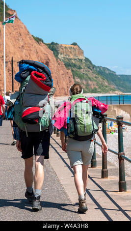 La ville de Sidmouth, Devon, Angleterre, Royaume-Uni. Juillet 2019. Jeune couple randonnées le long de la mer avec un fond de falaises du Jurassique à l'est du Devon Sidmouth. Banque D'Images