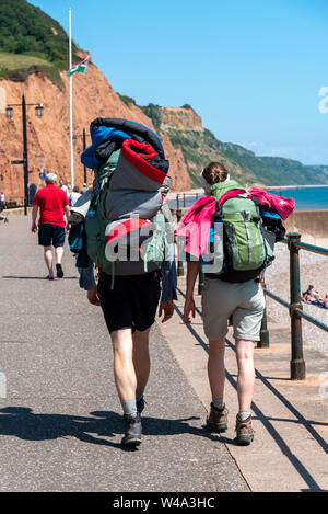 La ville de Sidmouth, Devon, Angleterre, Royaume-Uni. Juillet 2019. Jeune couple randonnées le long de la mer avec un fond de falaises du Jurassique à l'est du Devon Sidmouth. Banque D'Images