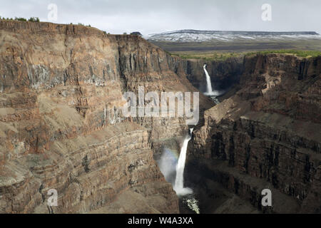 Cascade majestueuse en cascade dans le canyon accidenté entouré de montagnes enneigées dans le plateau de Putorana, au nord de la Russie, réserve naturelle de Putoranskiy. Banque D'Images