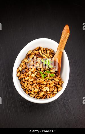 Graines de tournesol grillées et salées. Les graines de tournesol dans le bol sur le fond en bois. La nourriture végétalienne. Banque D'Images