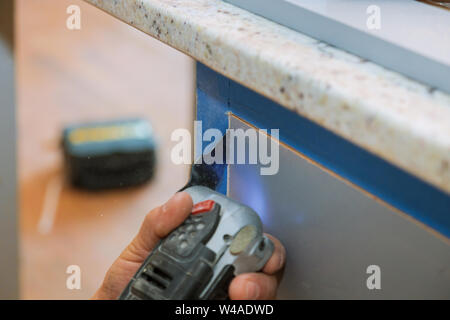 Coupe meubles multi fonctions oscillantes power tool sur l'ossature des armoires de cuisine Banque D'Images