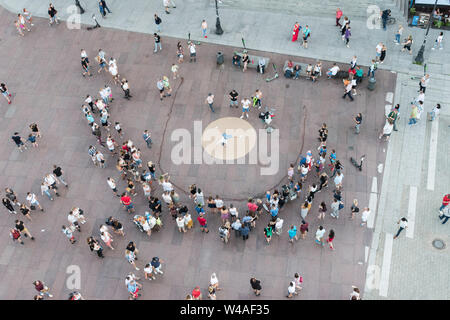 Une foule se rassemble dans une zone piétonne près de la Place du Château à Varsovie, Pologne, en tant qu'artiste de rue effectue des acrobaties sur ses mains. Banque D'Images