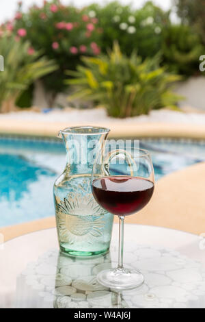 Carafe d'eau et de verre de vin avec piscine en arrière-plan Banque D'Images