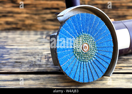 Meuleuse d'angle avec un disque de meulage des pinceaux et brosses fil abrasif se trouve sur le fond d'une vieille table en bois. Banque D'Images