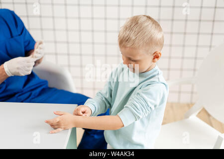 Patch médical. Médecin en uniforme bleu faire bandée élastique autour d'un garçon part avec son bras en traumatologie à l'hôpital. Banque D'Images