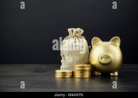 Piggy Bank et de l'argent sac avec des pièces en arrière-plan en bois foncé Banque D'Images