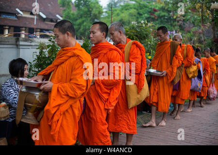 Les gens l'aumône aux moines bouddhistes dans la rue tôt le matin à Luang Prabang, Laos. Le rituel s'appelle Tak Bat. Banque D'Images