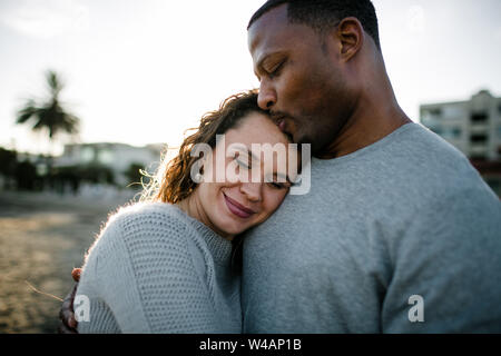 Couple raciale Multi embrasser sur la plage au coucher du soleil Banque D'Images