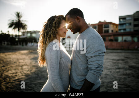 Couple raciale Multi embrasser sur la plage au coucher du soleil Banque D'Images