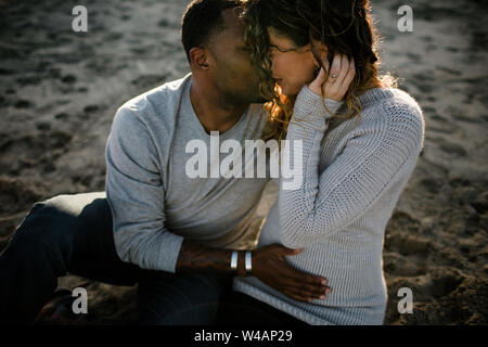 Couple raciale Multi embrasser sur la plage au coucher du soleil Banque D'Images