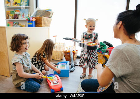 Bébé fille tenant une guitare interagit avec l'enseignant Banque D'Images