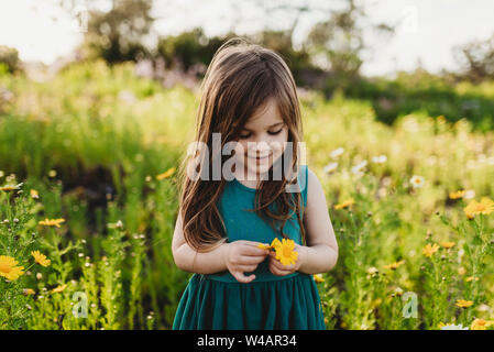 La mi-niveau de little girl holding flower et souriant à la bas Banque D'Images