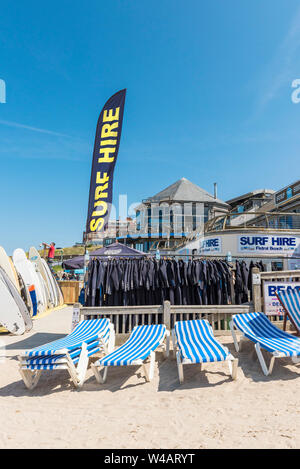 Planches, combinaisons et des chaises longues disponibles à la location à la location à Surf Fistral Newquay en Cornouailles. Banque D'Images