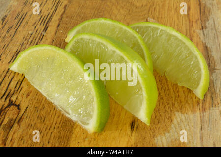 Couper les tranches de fruits fraîchement lime sur planche à découper en bois humide Banque D'Images