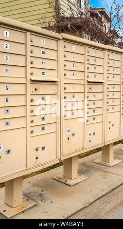 Châssis vertical de hauteur des boîtes aux lettres résidentielles avec compartiments numérotés sur le côté d'une route. Les maisons, les montagnes enneigées, et ciel nuageux ciel bleu peut être se Banque D'Images