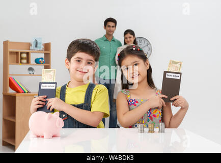 Deux enfants montrant le livre de banque et leurs parents dans le arrière-plan Banque D'Images