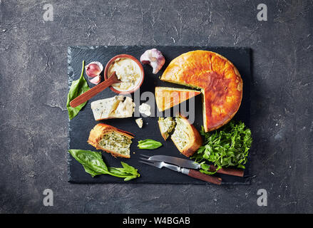 Haricots verts et épinards Tarte au fromage bleu ardoise noire en tranches sur un plateau avec crème au fromage bleu sauce dans un bol sur une table en béton, d'un point de vue horizontal Banque D'Images