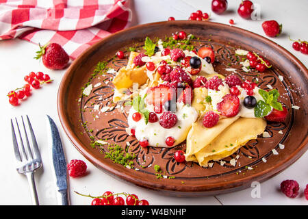 Crêpes maison avec de la crème et les baies sur fond blanc, close-up, photo horizontale Banque D'Images