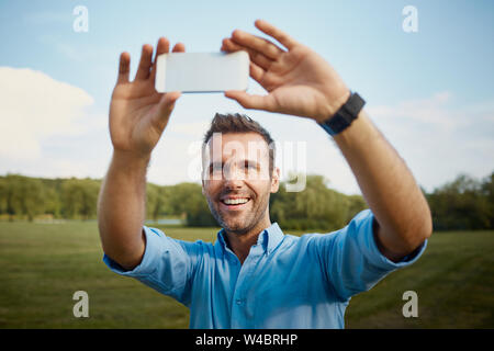 Happy Mid adult man prenant en selfies park Banque D'Images