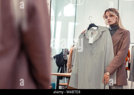 Femme blonde en miroir à lors de la recherche d'nouvelle robe Banque D'Images