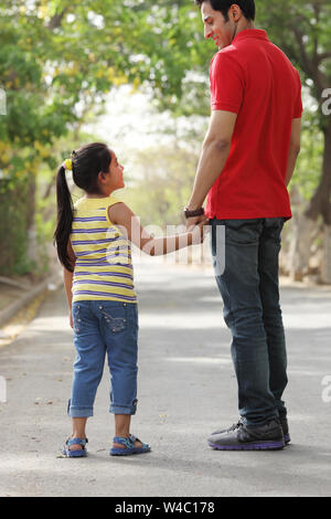 Rear view of a man walking on the road with his daughter Banque D'Images