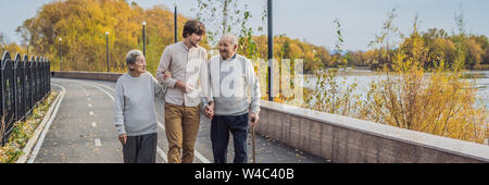 BANNER, format long un couple de personnes âgées des promenades dans le parc avec un homme assistant ou petit-fils adultes. La prise en charge des personnes âgées, le bénévolat Banque D'Images