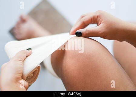 Le bandage de la plaie un genou blessé entorses / Premiers soins blessure à la jambe de la santé et en médecine concept Banque D'Images