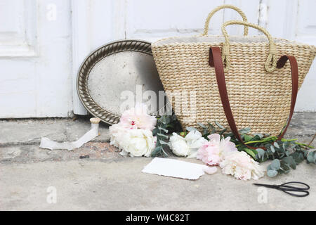 Mariage féminin vie encore avec la composition française sac panier de paille, fleurs de pivoines roses, eucalyptus, vintage silver tray avec de vieux ciseaux et soie Banque D'Images