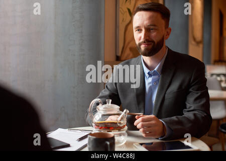 Homme en costume plateau boissons à partir d'un pot en verre. Banque D'Images