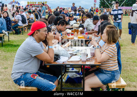 Les gens s'assoient à l'extérieur Table tréteau et manger des aliments de rue forme acheté cale à la Barrio Fiesta à Londres. Banque D'Images