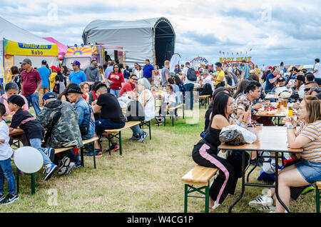 Les gens s'assoient à l'extérieur Table tréteau et manger des aliments de rue forme acheté cale à la Barrio Fiesta à Londres. Banque D'Images