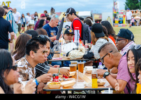 Les gens s'assoient à l'extérieur Table tréteau et manger des aliments de rue forme acheté cale à la Barrio Fiesta à Londres. Banque D'Images