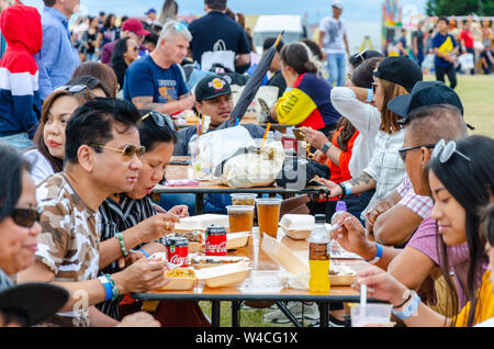 Les gens s'assoient à l'extérieur Table tréteau et manger des aliments de rue forme acheté cale à la Barrio Fiesta à Londres. Banque D'Images