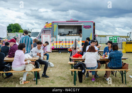 Une restauration mobile van vend des aliments de rue philippine. Les gens s'asseoir à des tables à tréteaux manger au Barrio Fiesta sur Londres Banque D'Images