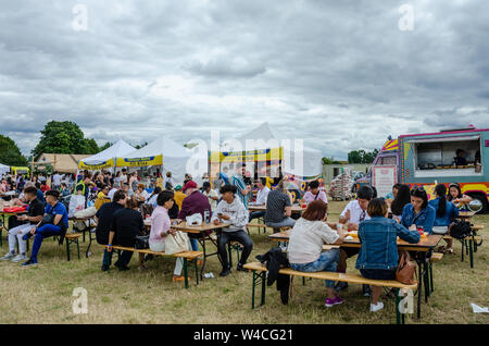 Les gens s'assoient à l'extérieur Table tréteau et manger des aliments de rue forme acheté cale à la Barrio Fiesta à Londres. Banque D'Images