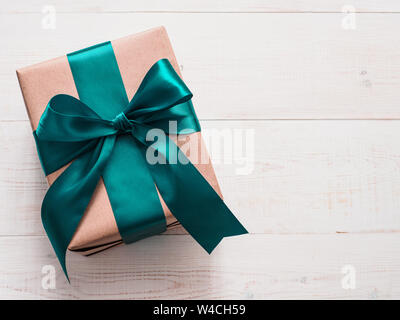 Boîte-cadeau dans l'artisanat du papier d'emballage et ruban de satin vert sur la table en bois blanc, copie espace droit. Beau Noël, Nouvel An ou cadeau d'anniversaire, laïcs ou Vue de dessus Banque D'Images