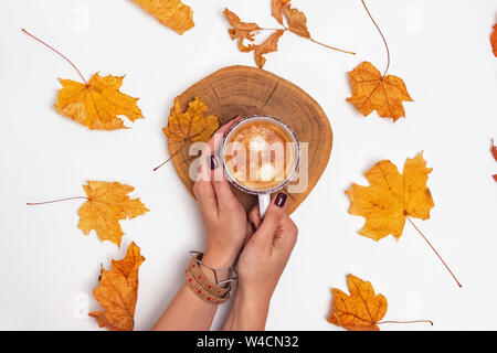 Woman's hands holding une tasse de café sur la table avec les feuilles jaunes, vue du dessus. Concept d'automne Banque D'Images