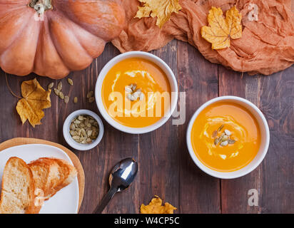 Deux bols de soupe au potiron maison delecious avec de la crème sur la table en bois Vue de dessus Banque D'Images