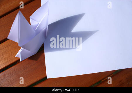 Papier Origami bird on wooden table Banque D'Images